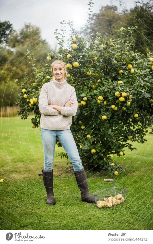 Portrait of smiling young woman at quince tree in garden - a Royalty Free  Stock Photo from Photocase