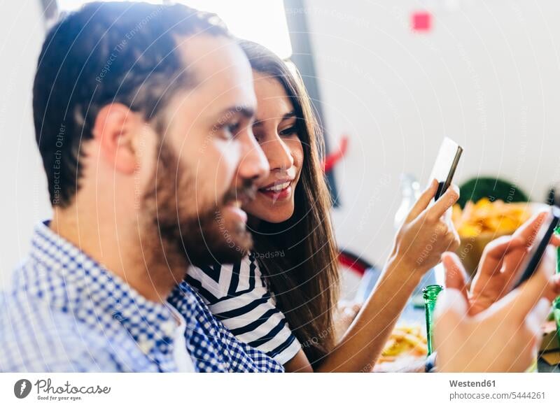 Couple looking at cell phone at dining table mobile phone mobiles mobile phones Cellphone cell phones Table Tables couple twosomes partnership couples