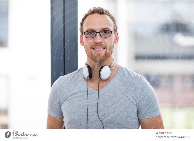 Young man with headphones around his neck, portrait cool attitude composed coolness laid-back young man young men Office Offices males Adults grown-ups grownups