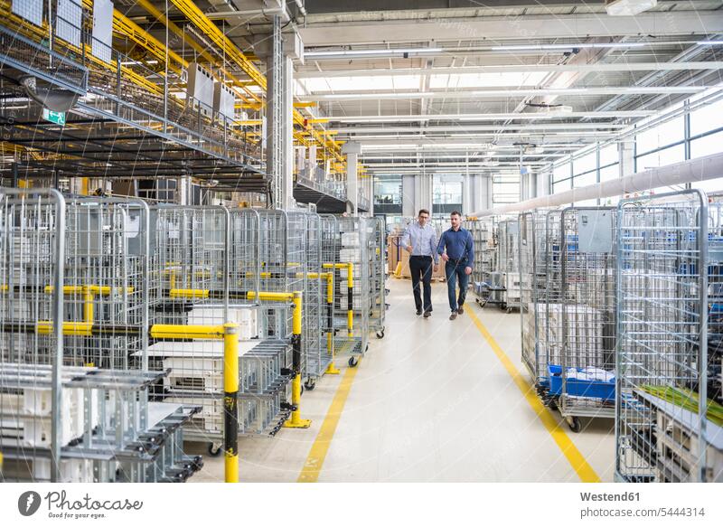 Two men walking in factory shop floor man males going factories working At Work Adults grown-ups grownups adult people persons human being humans human beings