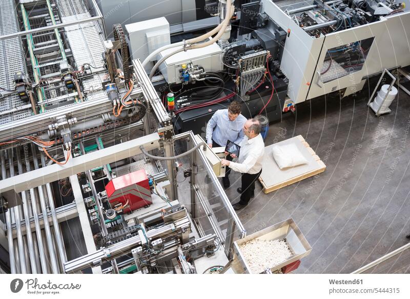 Top view of two men talking in factory shop floor factories speaking man males colleagues Adults grown-ups grownups adult people persons human being humans