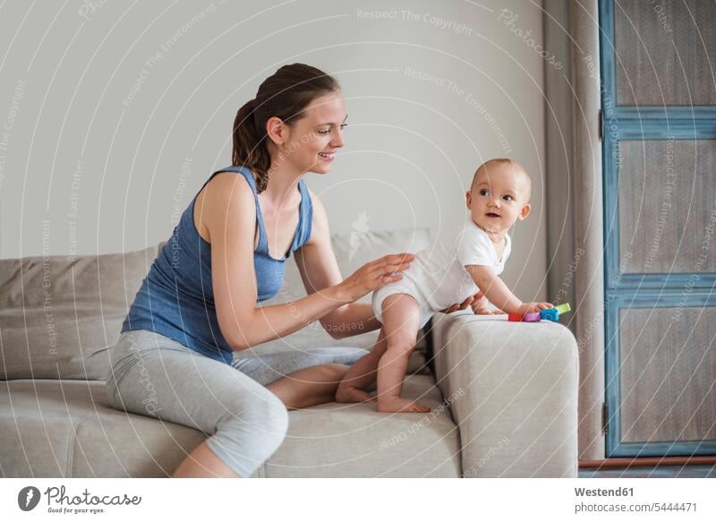 Happy baby girl with mother playing on couch settee sofa sofas couches settees smiling smile infants nurselings babies mommy mothers ma mummy mama people