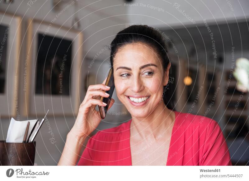 Mature woman sitting in cafe, talking on the phone females women Smartphone iPhone Smartphones call telephoning On The Telephone calling Adults grown-ups