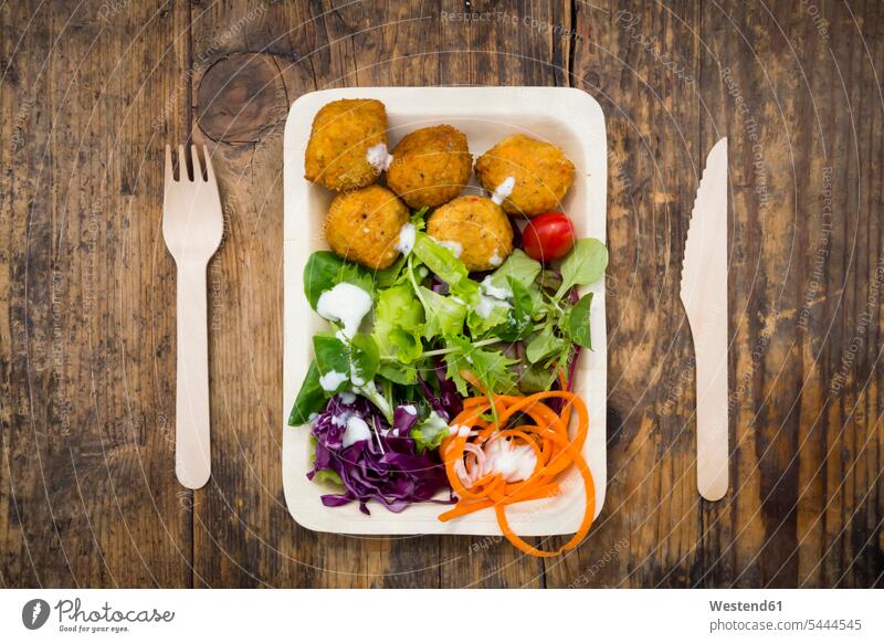 Falafel and salad on wooden disposable plates and cutlery nobody Snack Snacks Snack Food wooden plate small group of objects yogurt sauce yoghurt sauce