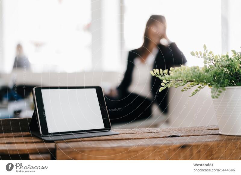 Businesswoman in cafe with digital tablet in foreground females women mobile working businesswoman businesswomen business woman business women At Work digitizer