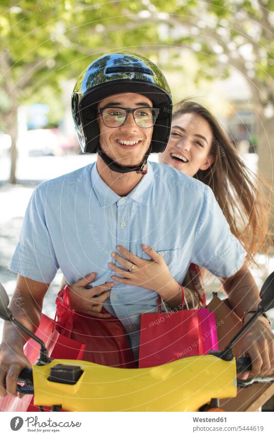 Happy young couple with shopping bags on motor scooter motor-scooter twosomes partnership couples happiness happy riding motor vehicle road vehicle