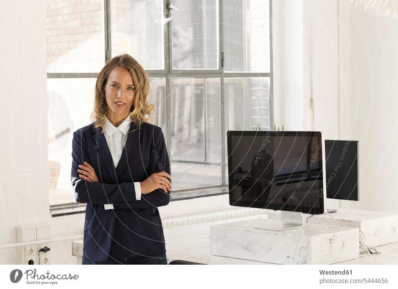 Businesswoman standing in her office with arms crossed offices office room office rooms businesswoman businesswomen business woman business women entrepreneur