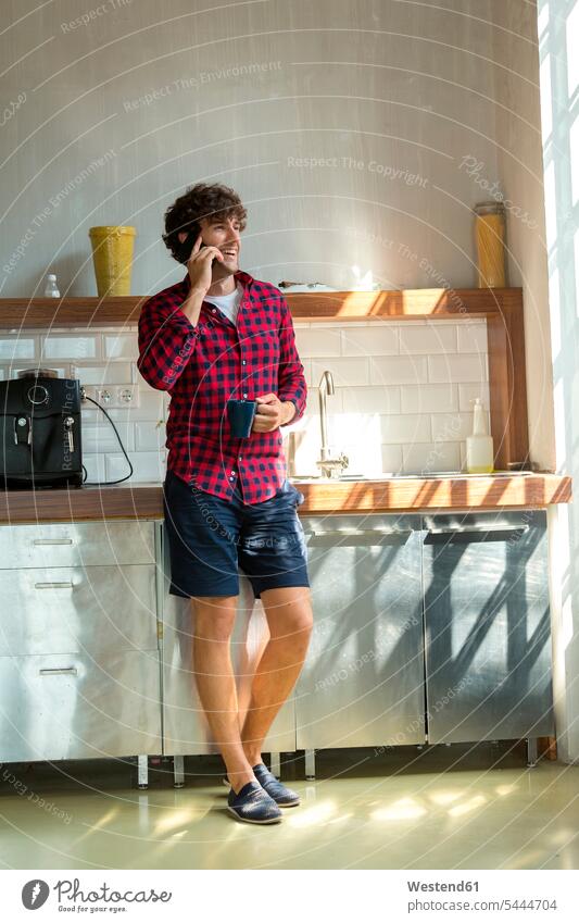 Young entrepreneur standing in company kitchen, drinking coffee, using smartphone young entrepreneur young entrepreneurs start-up entrepreneur on the phone call