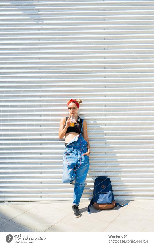 Young woman with soft drink and backpack females women drinking Adults grown-ups grownups adult people persons human being humans human beings Drink beverages