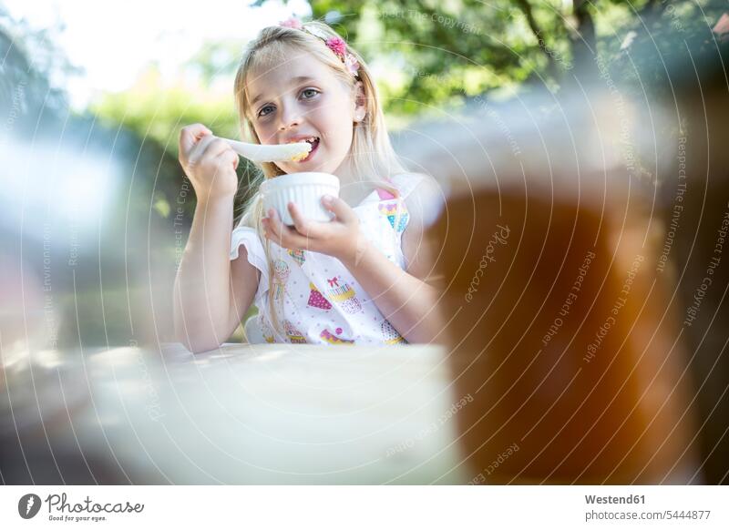 Girl eating at garden table girl females girls child children kid kids people persons human being humans human beings gardens domestic garden nutrition diet