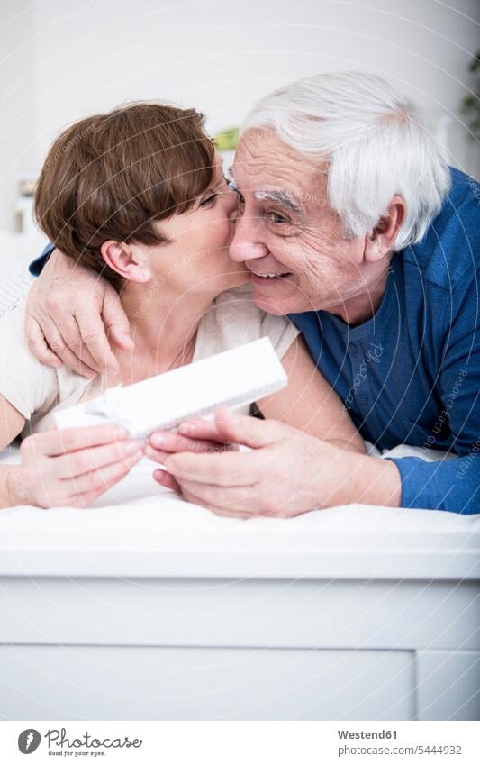 Senior couple lying in bed, man giving present to woman caucasian caucasian ethnicity caucasian appearance european bonding carefree beds relationship