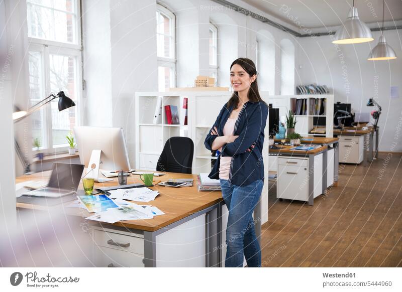 Portrait of confident woman standing in office offices office room office rooms workplace work place place of work females women smiling smile Adults grown-ups