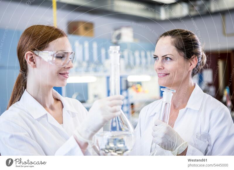 Two smiling scientists working together in lab laboratory At Work female scientists smile science sciences scientific woman females women workplace work place