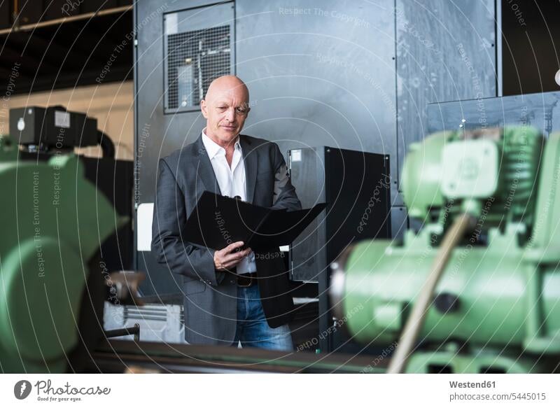 Man with clipboard at machine on factory shop floor clipboards clip-board clip-boards clip board man men males factories Adults grown-ups grownups adult people