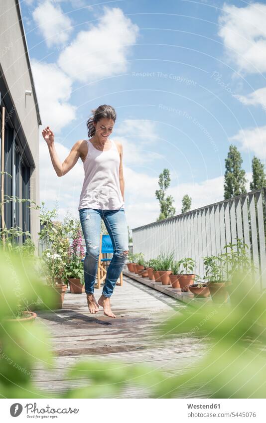 Happy woman jumping on balcony females women relaxed relaxation Leaping balconies Adults grown-ups grownups adult people persons human being humans human beings