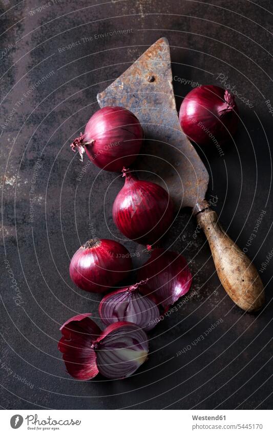Whole and sliced red onions and a rusty cleaver Shabby chic dark background Brown Background brown onion skin onion skins gleaming copy space metal metals