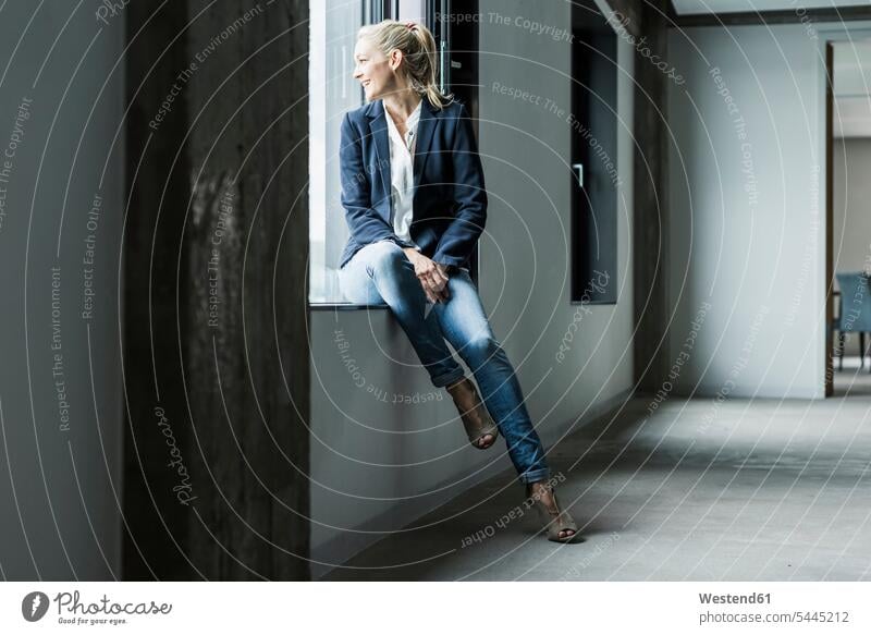 Smiling businesswoman looking out of window businesswomen business woman business women windows smiling smile business people businesspeople business world