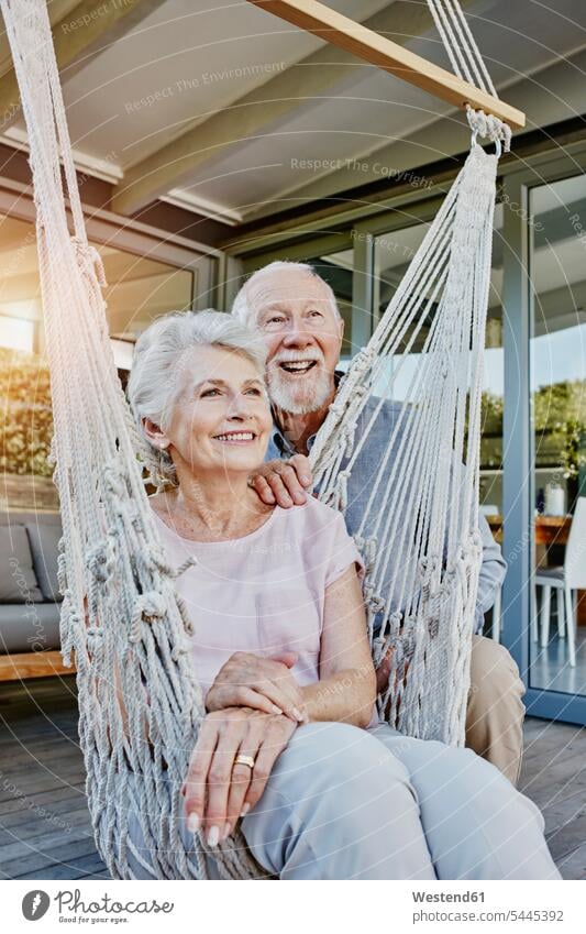 Senior couple on terrace, woman sitting in hammock terraces twosomes partnership couples Aging Ageing hammocks together Seated happiness happy senior adults
