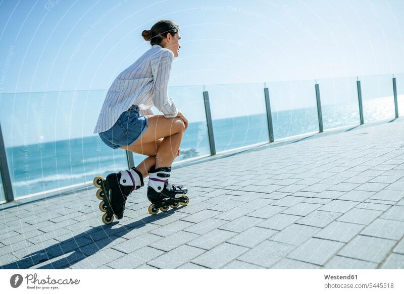 Young woman with inline skates on boardwalk at the coast females women inliners Adults grown-ups grownups adult people persons human being humans human beings