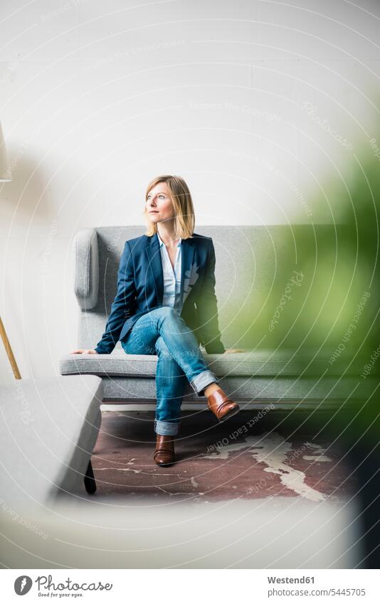 Businesswoman sitting on couch in office lounge businesswoman businesswomen business woman business women lounges Lounge Room settee sofa sofas couches settees