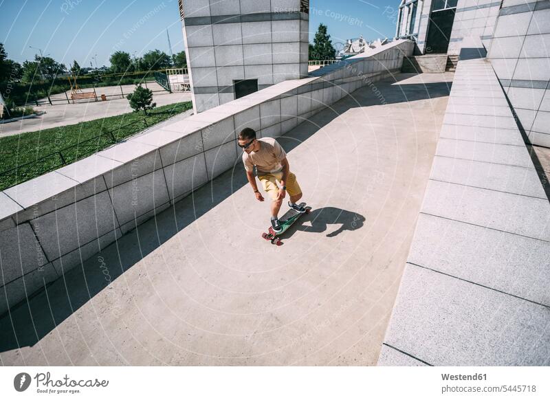 Young man riding skateboard in the city skateboarder skater skateboarders skaters men males Skate Board skateboards people persons human being humans