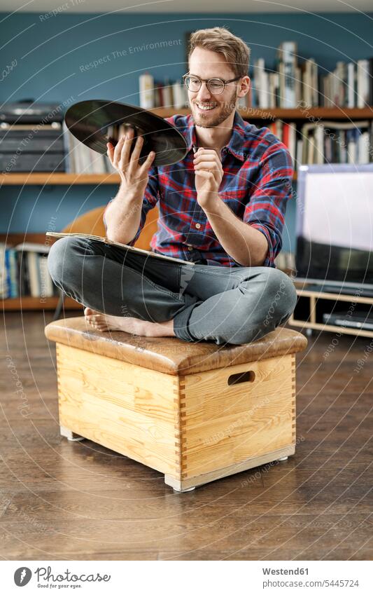 Smiling man at home holding vinyl record records men males sitting Seated analogue Media Adults grown-ups grownups adult people persons human being humans