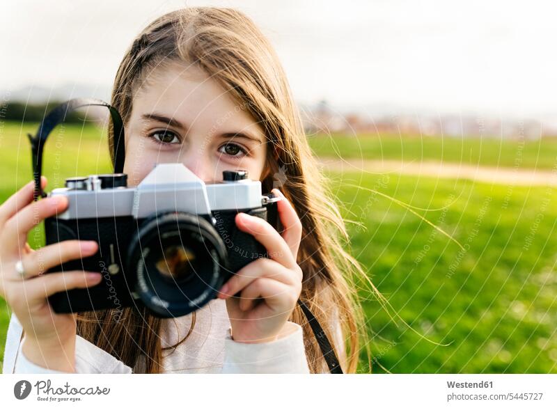 Portrait of a girl holding an old-fashioned camera outdoors females girls cameras portrait portraits photographing child children kid kids people persons