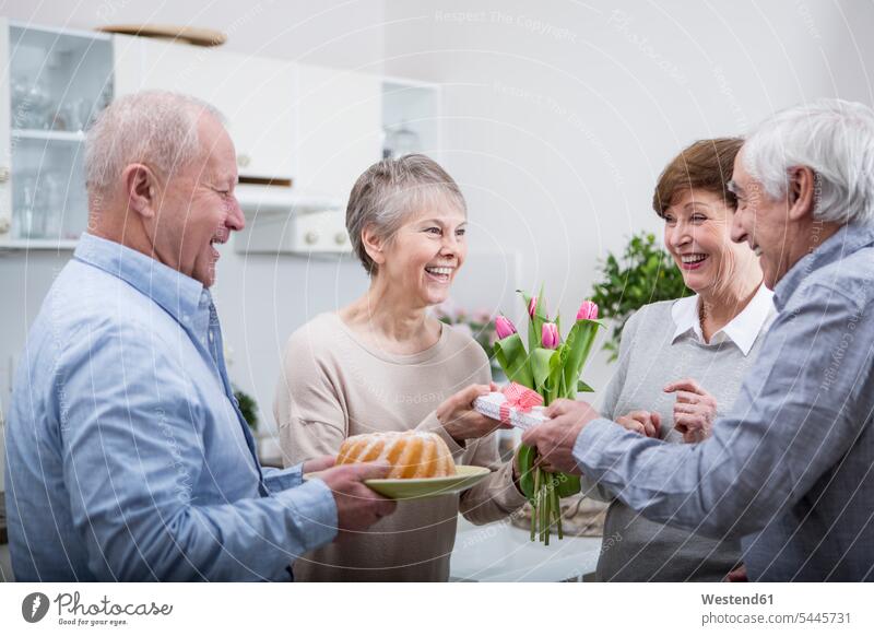 Two senior couples celebrating birthday party present Handing handing over handing out presenting hand over happiness happy senior adults seniors old Birthday