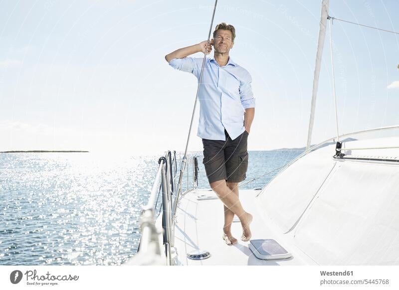 Mature man standing on sailing boat men males sailboat Sail Boat Sailboats sailing boats Adults grown-ups grownups adult people persons human being humans