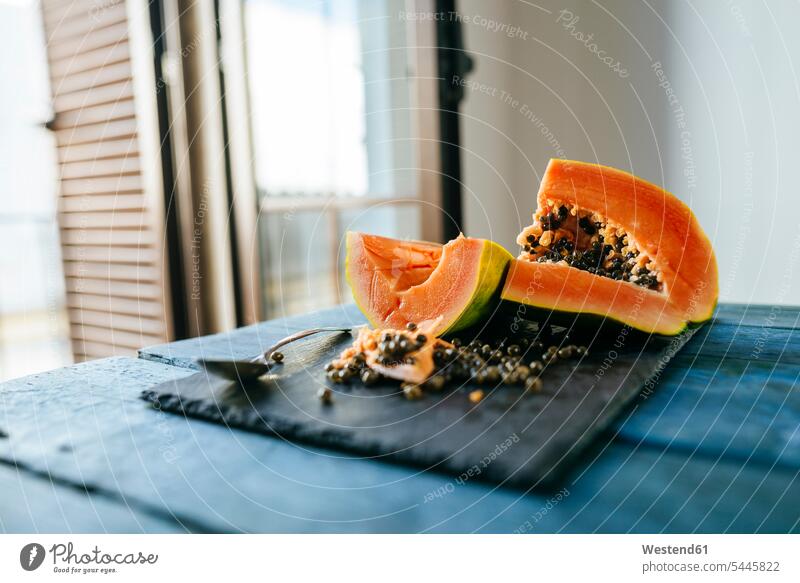 Papaya cut on slate on blue wood kitchen domestic kitchen kitchens copy space half halves halved wooden sliced preparation prepare preparing orange vitamines