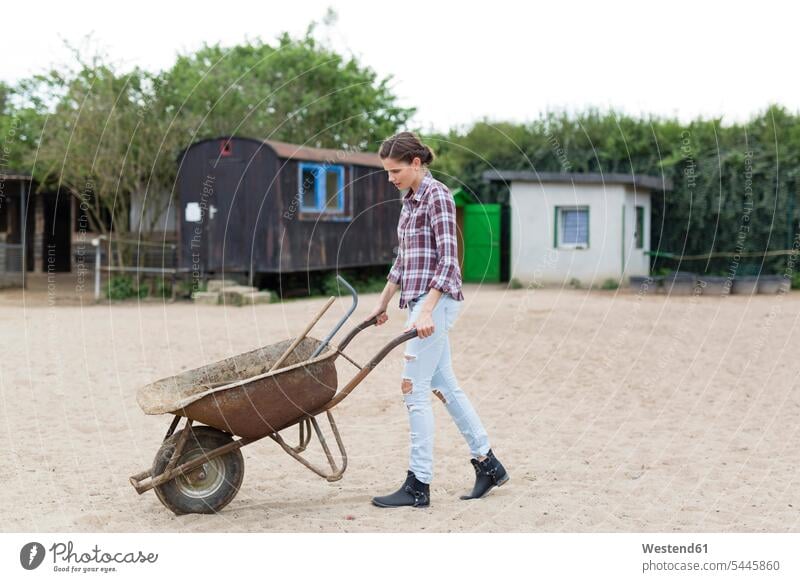 Woman walking with wheelbarrow on horse farm - a Royalty Free Stock ...