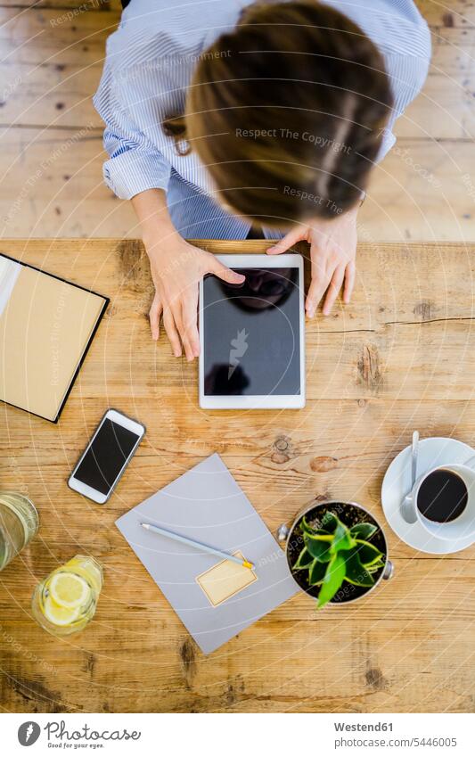 Top view of woman at wooden desk with notebook, cell phone and tablet mobile phone mobiles mobile phones Cellphone cell phones females women digitizer