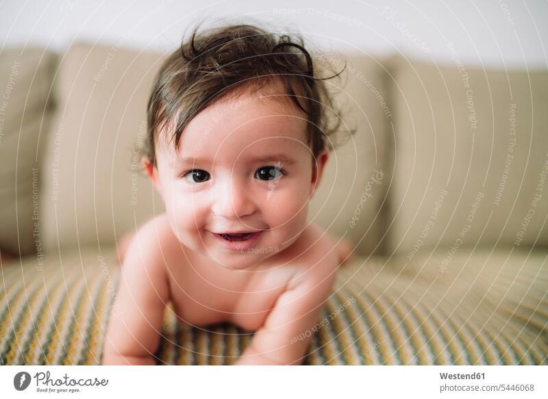 Portrait of smiling baby girl lying on couch settee sofa sofas couches settees baby girls female portrait portraits laying down lie lying down babies infants