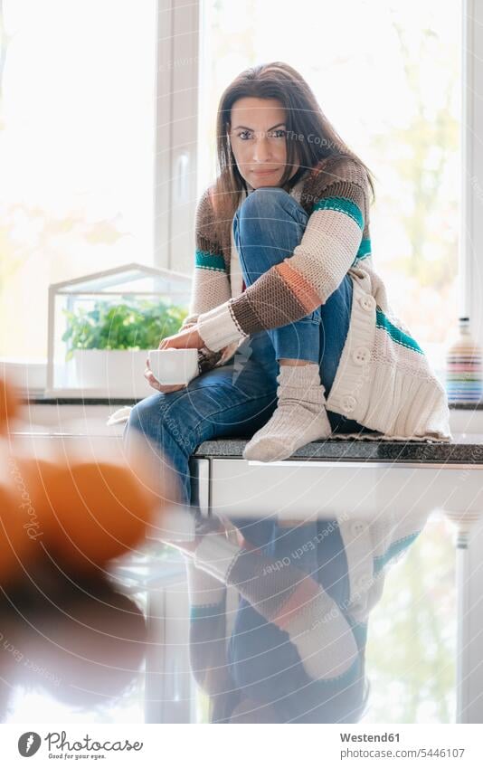 Portrait of woman at home sitting on kitchen counter portrait portraits Seated relaxed relaxation Coffee females women relaxing Drink beverages Drinks Beverage