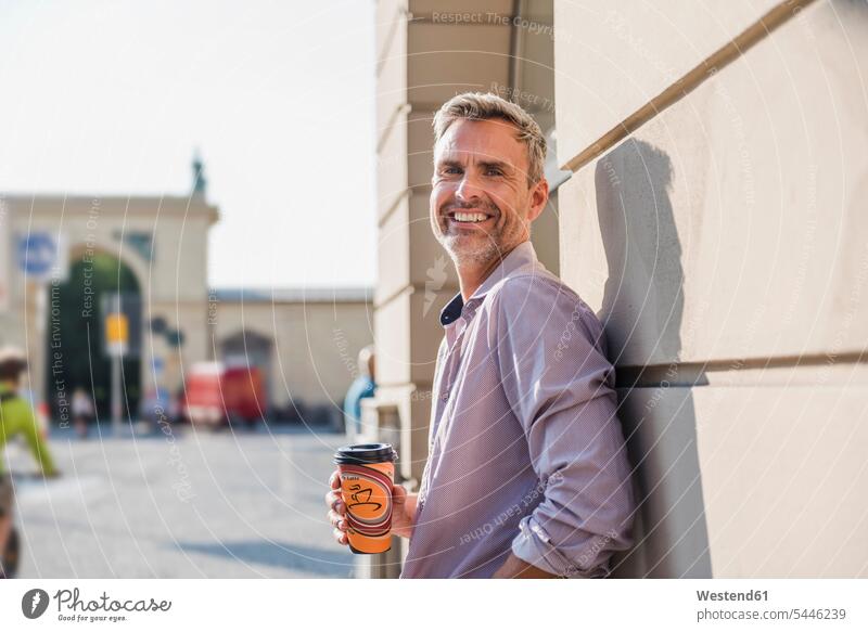 Smiling man with takeaway coffee in the city smiling smile men males town cities towns Coffee Adults grown-ups grownups adult people persons human being humans