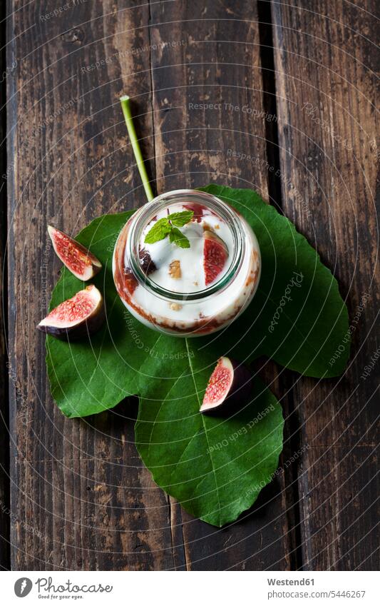 Glass of Mascarpone cream with fig compote and walnuts on fig leaf and dark wood food and drink Nutrition Alimentation Food and Drinks cinnamon stick