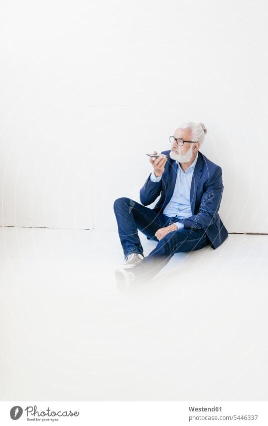 Mature man sitting on the floor using cell phone mobile phone mobiles mobile phones Cellphone cell phones Businessman Business man Businessmen Business men