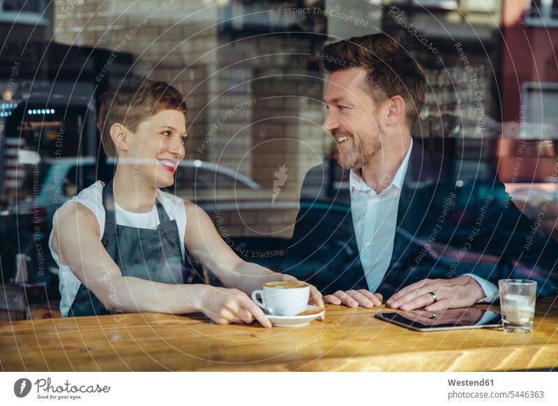 Waitress serving coffee to smiling customer in cafe Coffee portrait portraits smile waitress waitresses Businessman Business man Businessmen Business men Drink