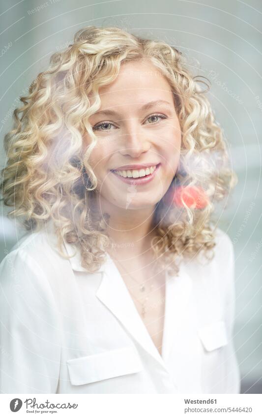 Portrait of smiling blond businesswoman behind windowpane portrait portraits businesswomen business woman business women business people businesspeople