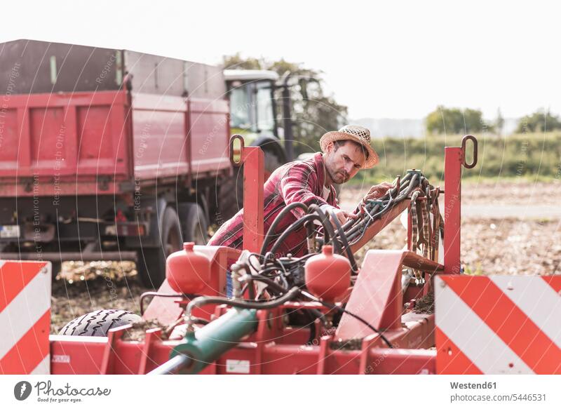 Farmer on field examining farm machine man men males Field Fields farmland Agriculture Machinery Agricultural Machinery farmer agriculturists farmers Adults