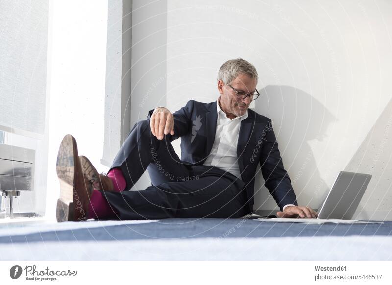 Businessman sitting on the floor using laptop wall walls Business man Businessmen Business men Seated Laptop Computers laptops notebook business people