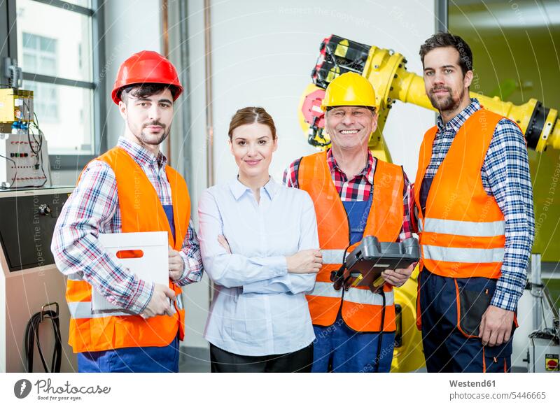 Portrait of confident staff in factory with industrial robot in background Robot working At Work factories smiling smile industry occupation profession