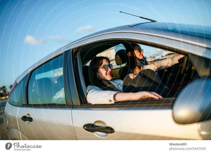 Two young women traveling in a car female friends automobile Auto cars motorcars Automobiles mate friendship motor vehicle road vehicle road vehicles