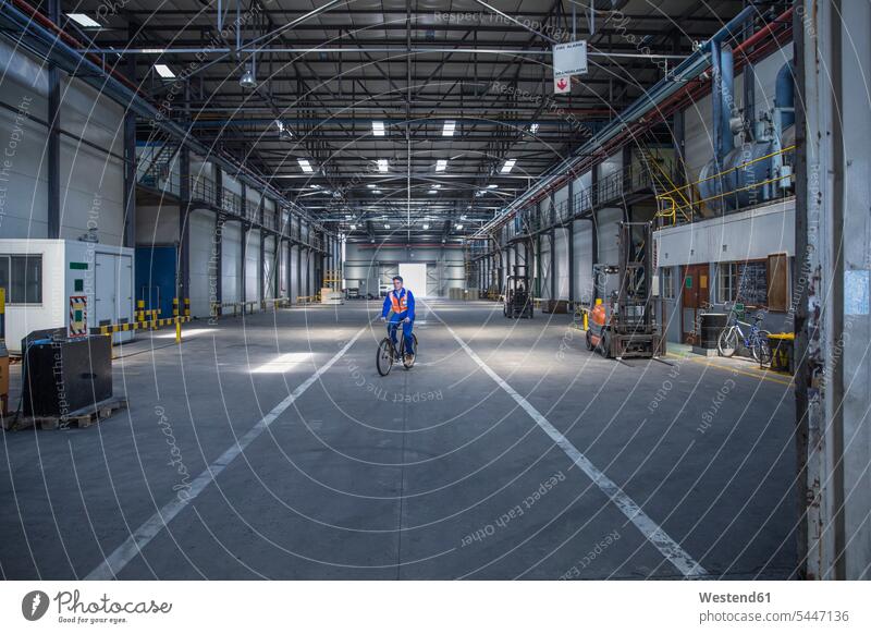 Worker on bicycle in warehouse factory bikes bicycles industrial hall shop floor factory hall industrial buildings industry halls built structure