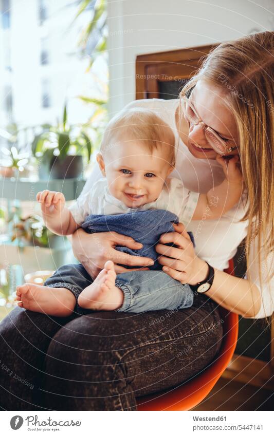 Portrait of smiling baby boy sitting on lap of his mother infants nurselings babies portrait portraits baby boys male people persons human being humans