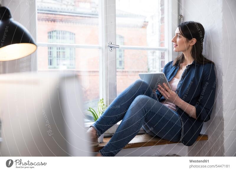 Woman with tablet looking out of window in office offices office room office rooms workplace work place place of work windows digitizer Tablet Computer