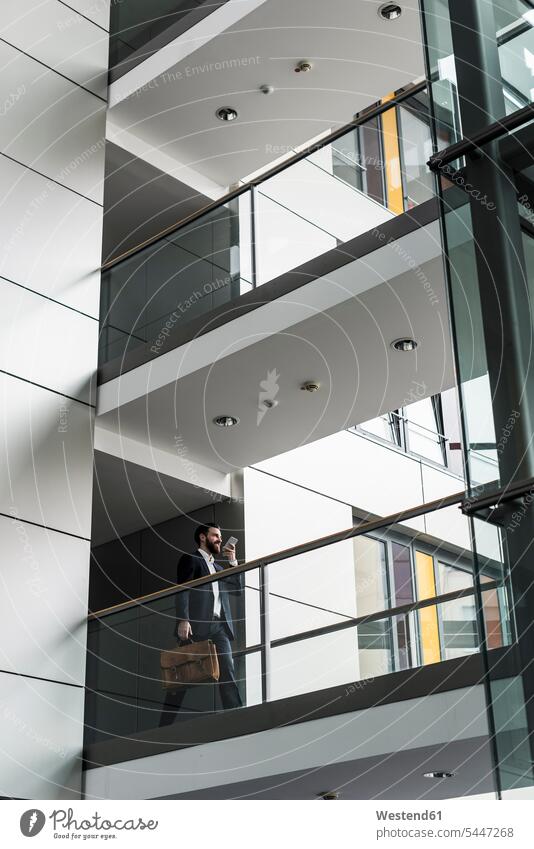 Businessman walking in office building, while using smart phone on the phone call telephoning On The Telephone calling office buildings Business man Businessmen