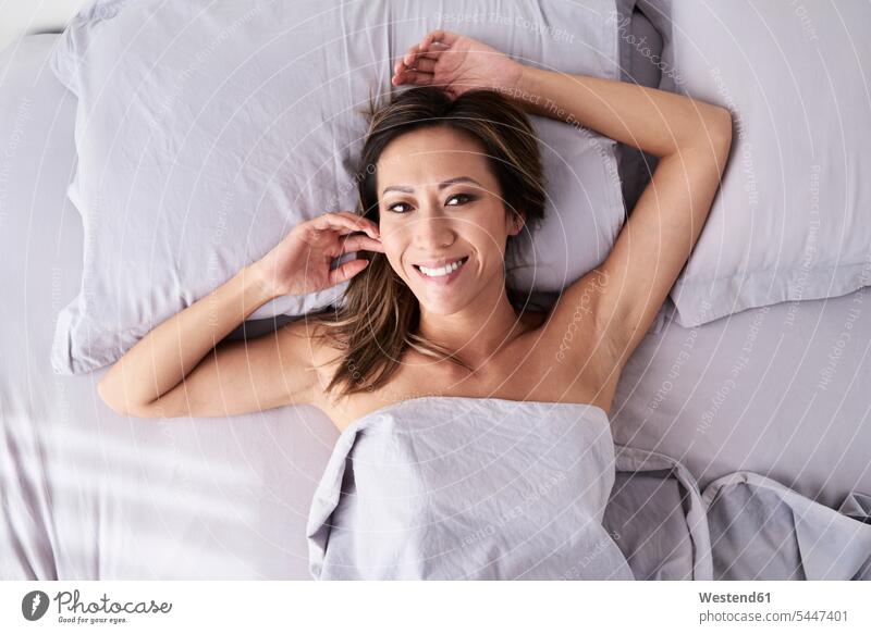 Portrait of smiling woman lying in bed without pyjama beds portrait portraits smile laying down lie lying down females women Adults grown-ups grownups adult