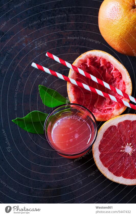 Whole and sliced Pink Grapefruit, leaves, straws and glass of grapefruit juice copy space Fruit Fruits healthy eating nutrition Leaf Leaves half halves halved