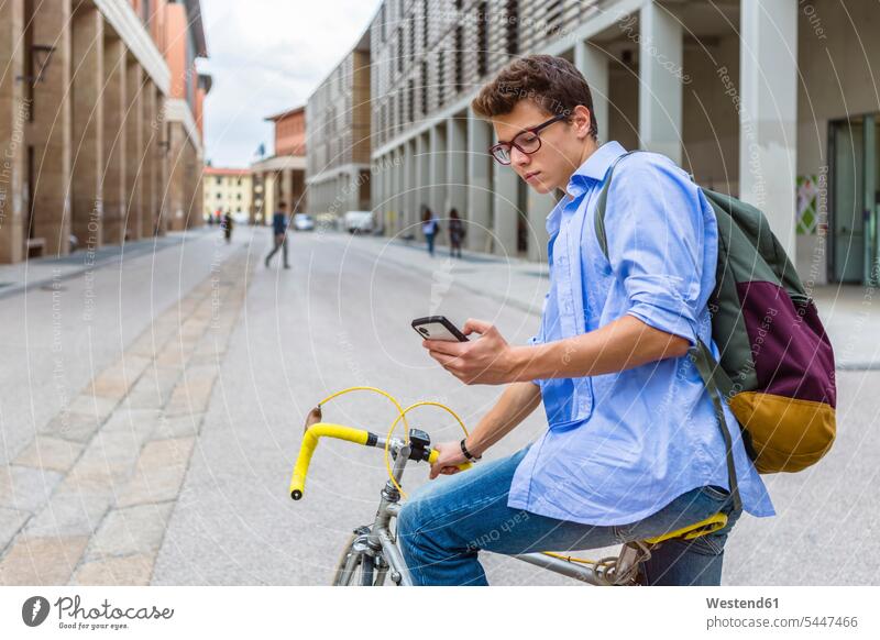 Young man on racing cycle looking at cell phone men males Adults grown-ups grownups adult people persons human being humans human beings serious earnest